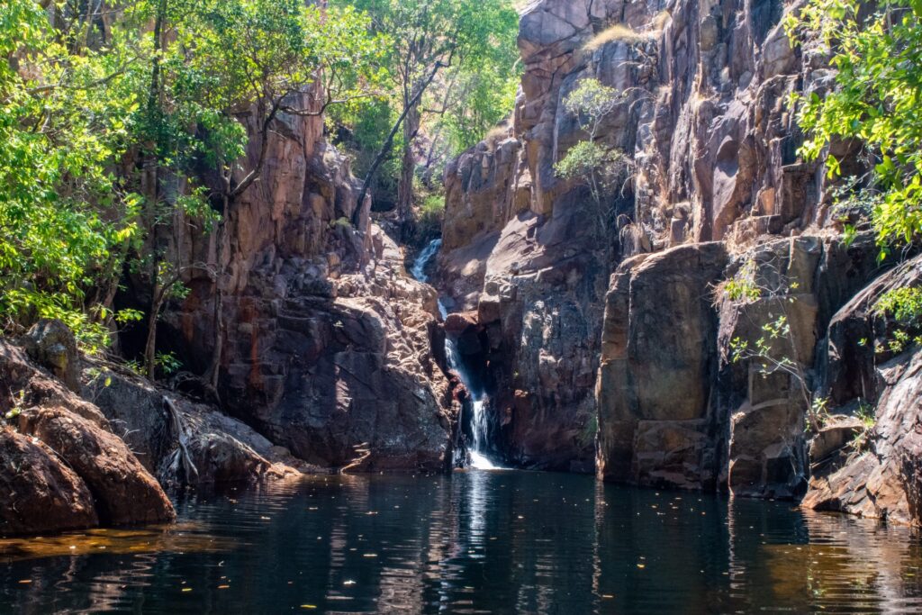 A thin waterfall runs through a small rocky gorge into a pool