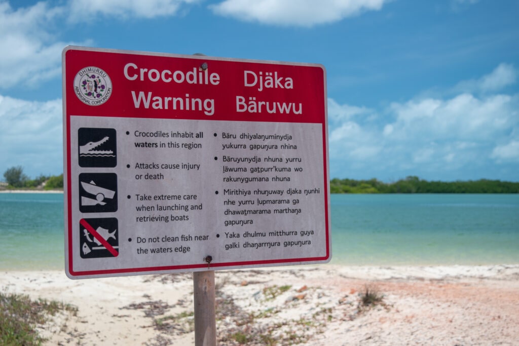 A sign near the ocean’s edge warns of crocodiles in both English and the local Indigenous language