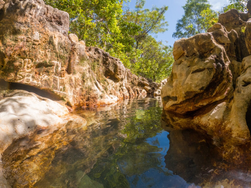 The photo is taken from a lagoon inside a small canyon surrounded by green trees