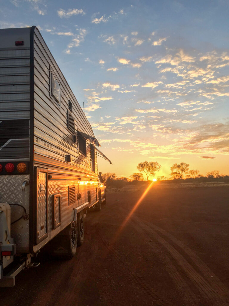 A sunset hits a caravan parked in a barren landscape