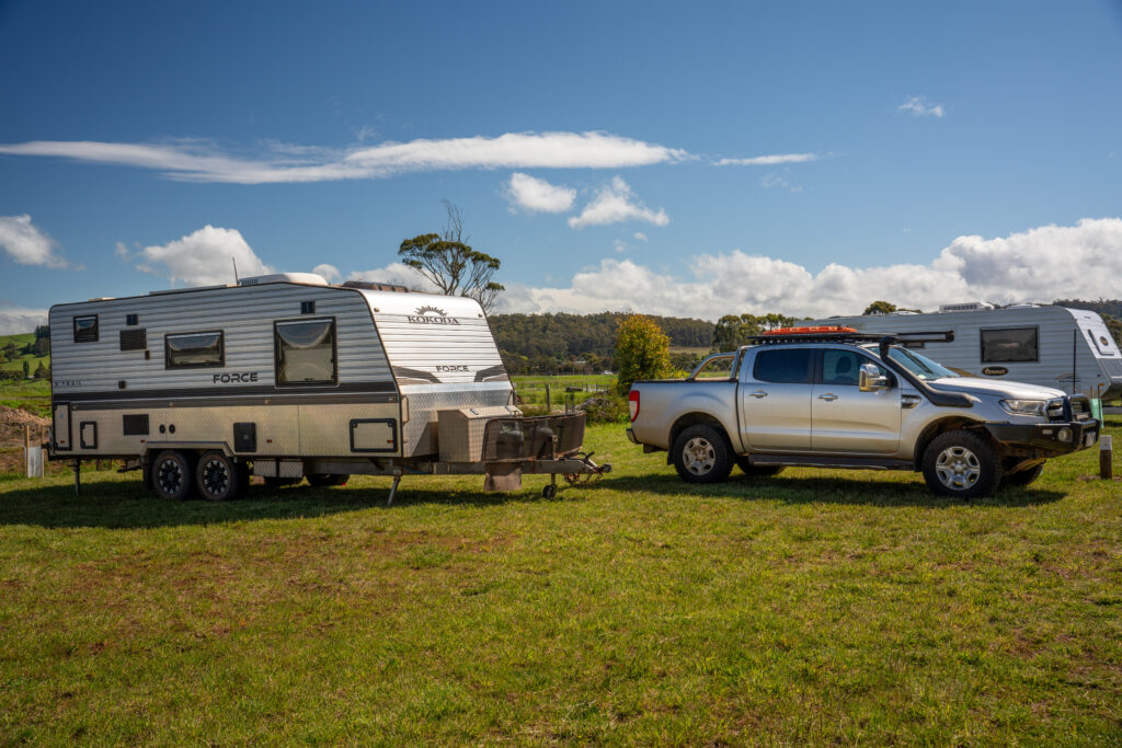 A silver and black 4x4 and caravan parked on grass at Turner Berry Patch in Tasmania, Australia