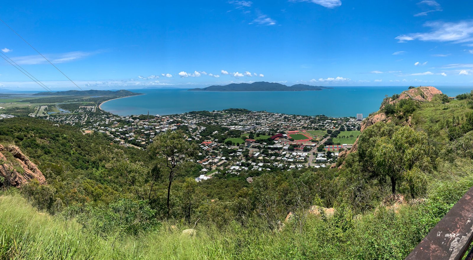 Views from a lookout looking down on Townsville and out to the ocean and a nearby green island on a mostly clear day